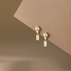 Detail of S925 silver vintage pearl earrings with a sparkling zircon and gold finish