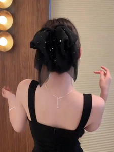 Detail of a large black fabric bow hair claw clip with sparkling rhinestones on long hair