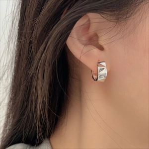 Macro side view of a geometric faceted 925 sterling silver hoop earring on model ear