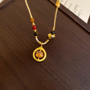 Detailed close-up of a gold-plated circular pendant with enamel inlay and colorful beads