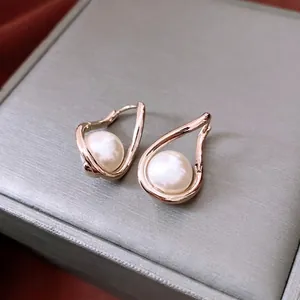 French style twisted rose gold earrings with pearl drop on a grey jewelry box surface
