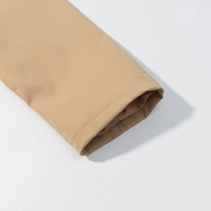 Détail des coutures sur les poignets d'un trench-coat camel avec texture de tissu tissé