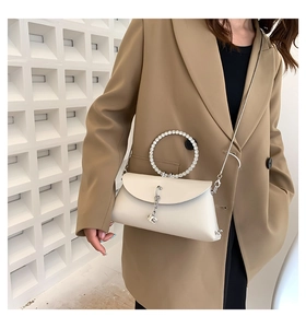 Detail of cream jelly handbag featuring a rhinestone ring handle and metal chain strap