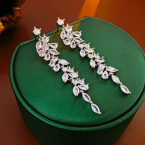 Detailed macro of silver tassel earrings with zircon crystals on green velvet box