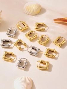 Close-up of minimalist U-shaped hoop earrings in gold and silver finish with shell decor