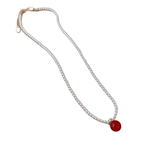 Elegant beaded pearl necklace with a striking red sphere pendant and gold clasp