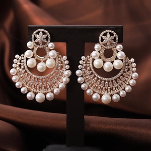 Elegant gold flower pearl drop earrings with rhinestones displayed on a professional stand