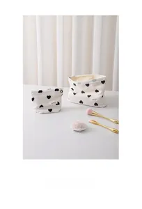 Macro view of textured cream canvas makeup bags with black heart prints and zipper closure