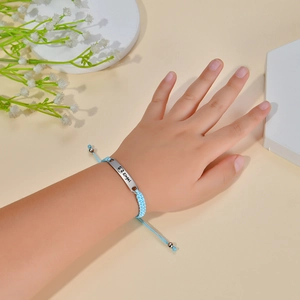 Detail of light blue braided rope bracelet with engraved silver plaque for children