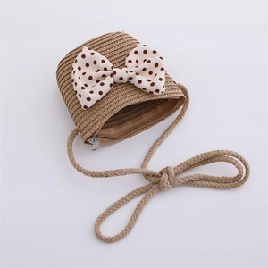 Detailed close-up of a brown straw woven crossbody bag with a black polka dot bow detail