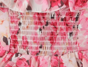 Detail van roze bloemenprint stof met elastische smocking en fijne stiksels
