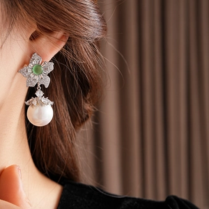 Gros plan de boucles d'oreilles vintage avec pierre verte et perle sur un mannequin