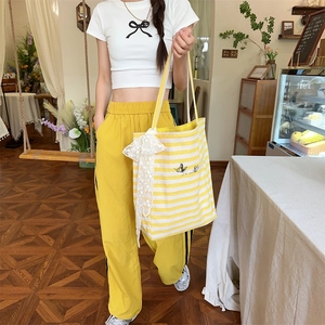 Detail of yellow striped canvas tote bag with lace bow and butterfly embroidery