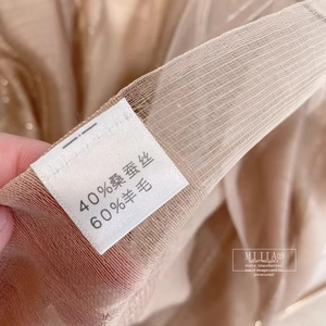 Detailed macro view of high-quality silk and wool blend fabric with wash care label