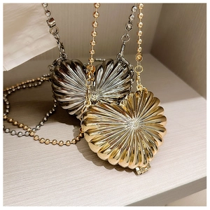 Detail of heart-shaped metal evening bags with pleated texture in gold and silver
