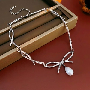 Elegant silver bow necklace with sparkling crystals and a large white pearl drop pendant