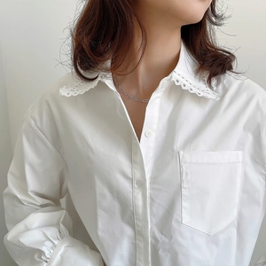 Close-up of women's white cotton shirt featuring a delicate lace embroidered collar detail