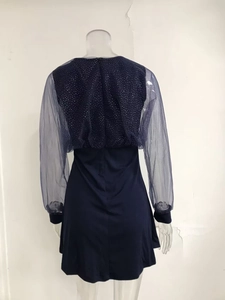 Detail of sheer mesh long sleeves with sparkling star pattern on a navy blue v-neck dress