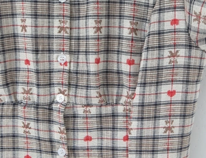 Detail of plaid fabric with bear and heart prints featuring a white resin button