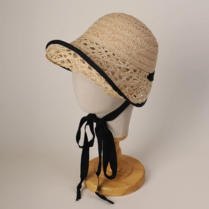 Detail of raffia straw hat showing breathable hollow knit texture and black ribbon ties
