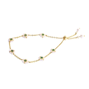 Elegant gold flower bracelet with emerald zircon and pearl accents on white background