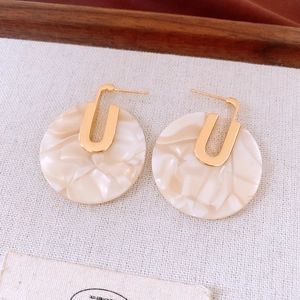 Detail of 18K gold-plated earrings with large ivory marble-textured acetate round drops
