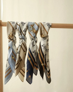 Detail of four silk neckerchiefs with classic horse carriage patterns hanging on a wooden rod
