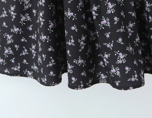 Detail of floral printed fabric with purple flowers on a black background dress