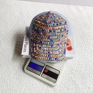 Detail view of denim baseball cap with colorful rhinestones and pearls on a digital scale