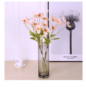 Detail of light pink artificial poppies in a smokey grey glass vase for home decor
