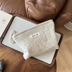 Detailed texture of off-white linen cosmetic bag with a simple wish fabric label