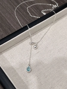 Detailed macro view of S925 silver necklace with light blue teardrop pendant and beads