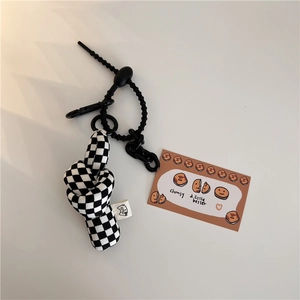 Detail of checkered plush keychain with cat woven label and black plastic chain link