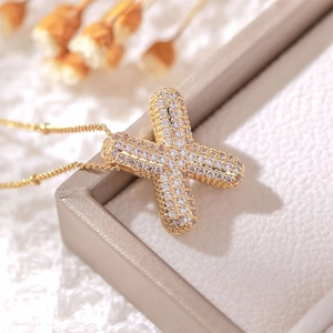 Macro shot of 18k gold plated cross pendant with shimmering cubic zirconia crystals