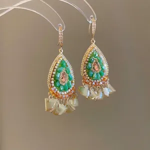 Detail of bohemian gold earrings with green resin beads and pink crystal charms