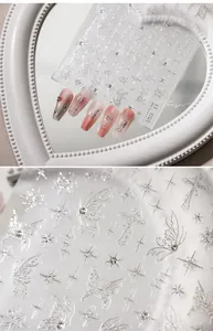 Close-up of 3D metallic butterfly and star nail stickers with rhinestones on model nails