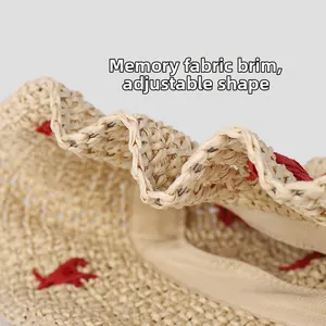 Detail of beige straw hat featuring shapeable brim with memory wire and red embroidery