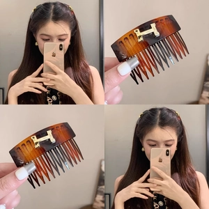 Close-up of tortoiseshell hair comb with a vintage gold letter H metal inlay detail