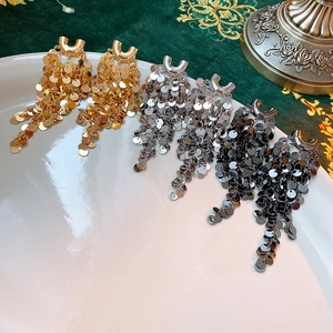 Detailed close-up of U-shaped metal sequin fringe earrings in gold, silver, and gunmetal black