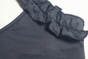 Detail of ruffled shoulder strap on black bodycon dress with knit fabric texture