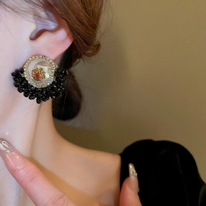 Vintage palace style floral earrings with red gems and black crystal beads in warm light