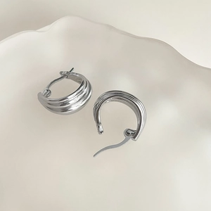 Macro detail of silver layered wave earrings with a vintage textured metallic finish