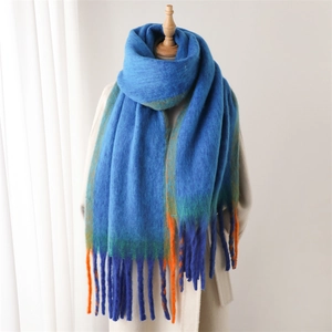 Detail of blue gradient cashmere-like scarf showing soft texture and long orange tassels