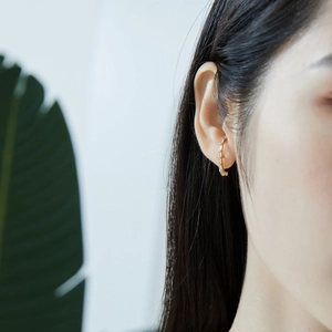 Close-up of a gold geometric earring with square cubic zirconia on a model ear