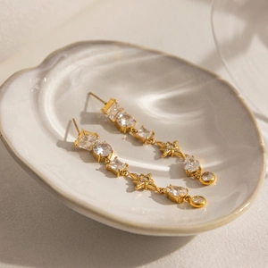 Détail macro de boucles d'oreilles étoile 18K or et zircons sur une coupelle en céramique