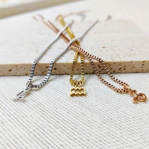 Detailed view of 18k gold, silver, and rose gold zodiac pendants on box chains