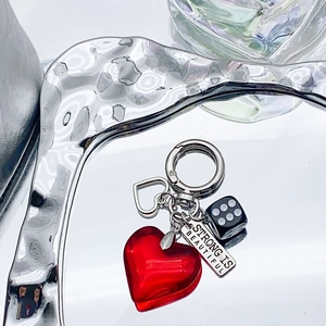 Red heart and dice charm keychain with Strong Is Beautiful engraving on metallic surface