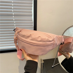 Pink nylon crossbody chest bag with adjustable strap and decorative zipper detail