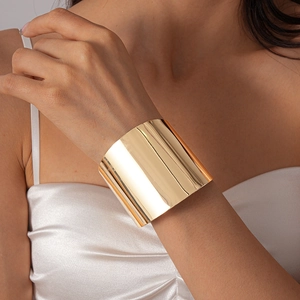 Gros plan d'un large bracelet manchette doré poli sur un mannequin en soie blanche