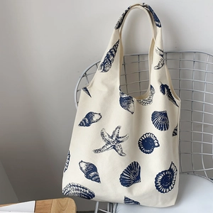 Close-up of off-white canvas tote bag with deep blue sea shell and starfish prints